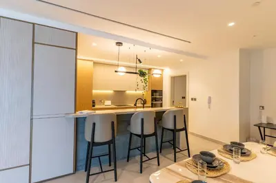 a kitchen and living room with a bar and stools at 3BR apartment in the one of the tallest tower in Marina in Dubai
