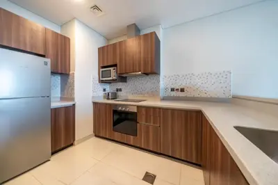 a kitchen with wooden cabinets and a stainless steel refrigerator at Prestige Heights 1BR with Iconic Oceanview in Dubai