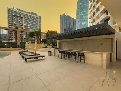 a rooftop patio with chairs and a bar on a building at Luxury 1BR Paragon by IGO BURJ khalifa View in Dubai