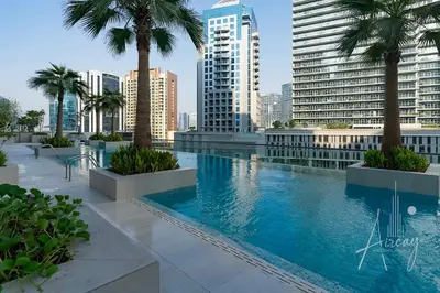a large swimming pool with palm trees and buildings at Sleek & Glam Downtown Studio Near Burj Khalifa in Dubai