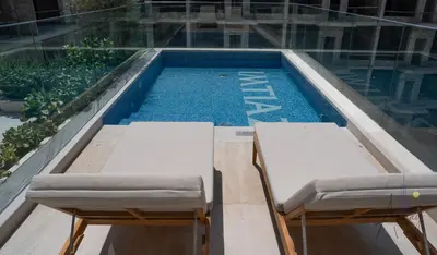 a swimming pool with two beds in front of a building at Boutique 1BR Escape Cosy & Classy JVC in Dubai