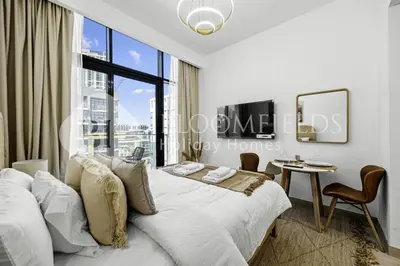 a bedroom with a bed and a table and a window at Bloomfields Modern STU Azizi Riviera in Dubai