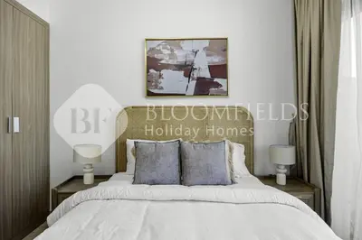 a bedroom with a bed with two night stands and two lamps at Bloomfields Modern STU Azizi Riviera in Dubai