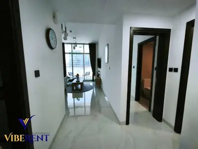 a hallway with a table and a clock on a wall at Supreme joy in Arjan 1 BHK in Dubai
