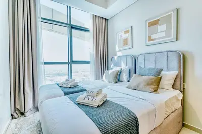 two beds in a room with a large window at PVH - City View Contemporary 2BR - Aykon Tower C in Dubai