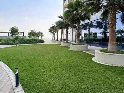 a park with palm trees in front of a building at PVH - City View Contemporary 2BR - Aykon Tower C in Dubai