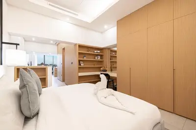 a bedroom with a white bed and wooden cabinets at Luxe Royal Amwaj Palm Jumeirah Beach Access in Dubai