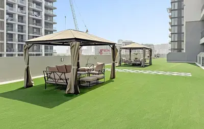 a patio with chairs and umbrellas on a roof at Swanky Studio with Balcony in Dubai Hills Estate in Dubai