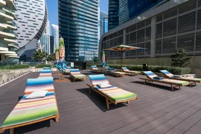 a row of chaise lounges and umbrellas on a deck at Balcony Facing a Partial Canal View, Close to Metro and Marine Transport, Downtown Attractions Just a Ride Away, Urban Oasis, Business Bay by Deluxe Holiday Homes in Dubai