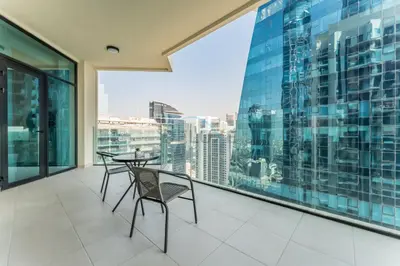 a balcony with a table and chairs and a large window at Balcony Facing a Partial Canal View, Close to Metro and Marine Transport, Downtown Attractions Just a Ride Away, Urban Oasis, Business Bay by Deluxe Holiday Homes in Dubai