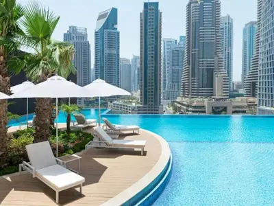 a pool with chairs and umbrellas and a city skyline at Modern 1BR in Dubai Marina near to Dubai Harbour in Dubai