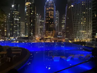 a large pool with blue lights in a city at night at Modern 1BR in Dubai Marina near to Dubai Harbour in Dubai