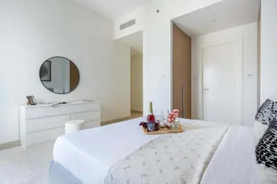 a white bedroom with a white bed and a mirror at Frank Porter - Grove at Creek Beach Building in Dubai