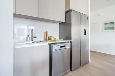 a kitchen with white cabinets and a stainless steel refrigerator at Frank Porter - Grove at Creek Beach Building in Dubai
