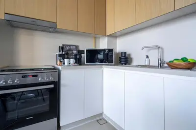 a kitchen with white cabinets and a stove and a sink at Frank Porter - 5242 Emaar Tower in Dubai