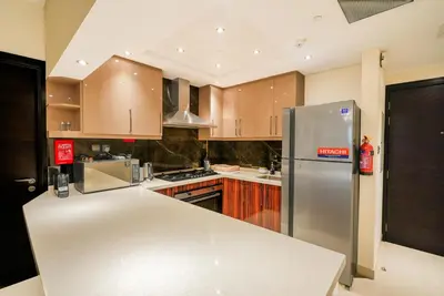 a kitchen with wooden cabinets and a stainless steel refrigerator at Escape24 2BR with Large Balcony near Burj Khalifa in Dubai