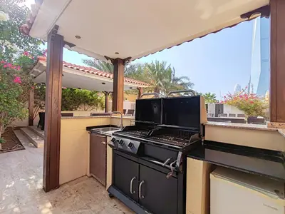 an outdoor kitchen with a stove and an outdoor patio at Luxury 7BD Pool villa in Marina, Huge Garden with Barbeque in Dubai