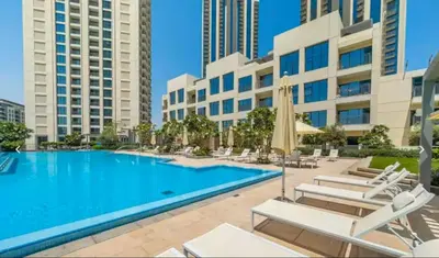 a swimming pool with chairs and a building at Vogue Creek Harbour Icon Bay Waterfront Living Close to Downtown, Burj Khalifa and Dubai Mall, Two Bedroom Apartment with Large Balcony and Canal View, Access to all Amenities in Dubai