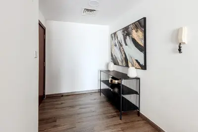 a living room with white walls and a large painting on the wall at Beautiful 2 bed in JBR! bahar in Dubai