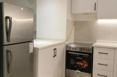 a kitchen with white cabinets and a stainless steel refrigerator at City Stay Dubai South - Serviced Apartments in Dubai