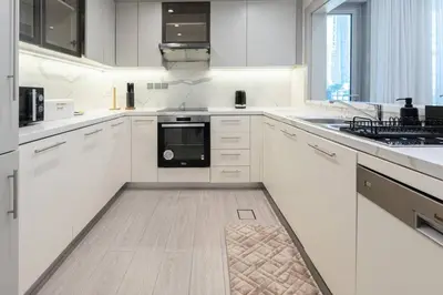 a kitchen with white cabinets and a black appliance at 1 BR Near Burj Khalifa & Dubai Mall - Downtown in Dubai