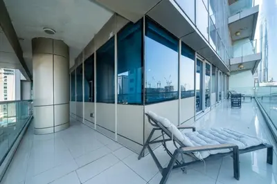 a room with a chair in a building with windows at Spacious 2-Bed Marina Home with Wrap-Around Balcony in Dubai