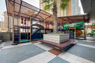 a playground with a slide and a tree in a building at Spacious 2-Bed Marina Home with Wrap-Around Balcony in Dubai