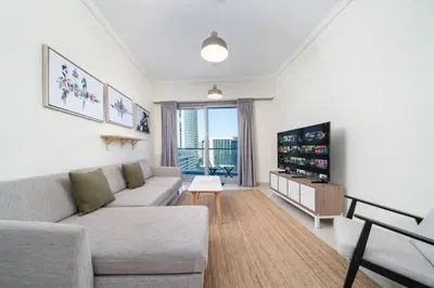 a living room with a couch and a tv at Spacious 2-Bed Marina Home with Wrap-Around Balcony in Dubai