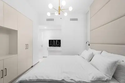 a white bedroom with a large bed and a chandelier at The Iconic View - 3BR With Maid's Room - Burj Khalifa Area in Dubai