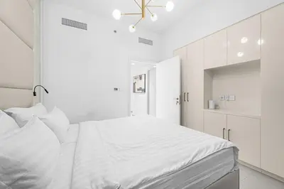 a white bedroom with a large bed and white cabinets at The Iconic View - 3BR With Maid's Room - Burj Khalifa Area in Dubai