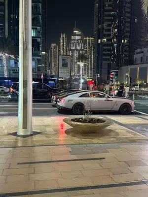 a white car driving down a city street at night at Great 1 bed apart close to Burj Khalifa and Dubai Mall in Dubai