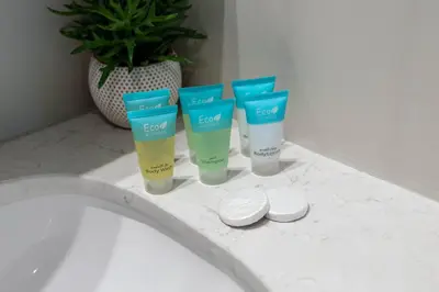 four bottles of sunscreen sitting on a counter next to a sink at Luxury 1BR with Private Beach & Pool! in Dubai