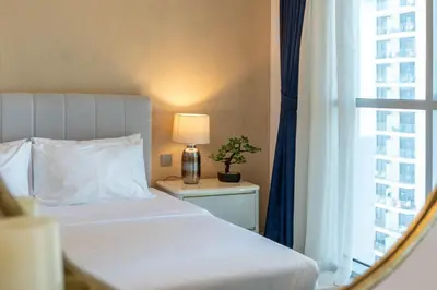 a bedroom with a bed with a lamp and a window at Luxury 1BR with Private Beach & Pool! in Dubai