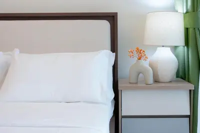 a bed with a white pillow and a table with a lamp at Modern Studio in Azizi Riviera 46 with Pool, Gym & Free Parking in Dubai