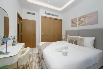 a bedroom with a large white bed and a desk at Perfectly Positioned Near the Park and Meydan Racecourse, Just a 20-Minute Drive to Global Village, Azizi Riviera 65, Al Merkadh by Deluxe Holiday Homes in Dubai
