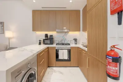 a kitchen with a stove and a washing machine at Perfectly Positioned Near the Park and Meydan Racecourse, Just a 20-Minute Drive to Global Village, Azizi Riviera 65, Al Merkadh by Deluxe Holiday Homes in Dubai