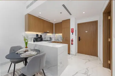 a kitchen with a table and chairs in a kitchen at Perfectly Positioned Near the Park and Meydan Racecourse, Just a 20-Minute Drive to Global Village, Azizi Riviera 65, Al Merkadh by Deluxe Holiday Homes in Dubai