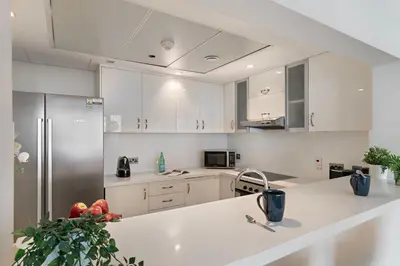 a kitchen with white cabinets and a refrigerator at The Smart Concierge - Marina tower in Dubai