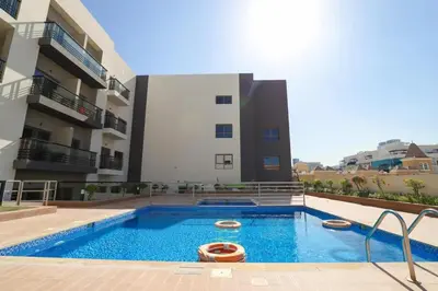 a swimming pool in front of a building at Joya Verde Residence - Studio with Balcony in Dubai