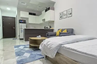 a bedroom with a bed and a table and a kitchen at Joya Verde Residence - Studio with Balcony in Dubai