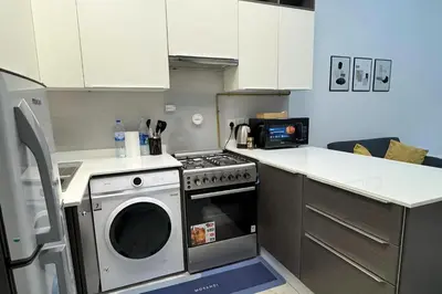 a kitchen with a stove and a washing machine at Joya Verde Residence - Studio with Balcony in Dubai