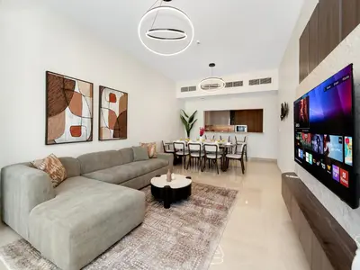 a living room with a couch and a flat screen tv at Royal Vista - Luxe 4BR Penthouse with Burj Khalifa View at Imperial Avenue - Downtown in Dubai