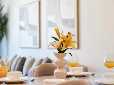 a table with a vase of flowers and glasses of orange juice at Royal Vista - Luxe 4BR Penthouse with Burj Khalifa View at Imperial Avenue - Downtown in Dubai