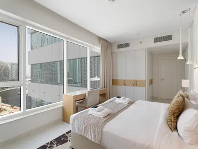 a bedroom with a large bed and large windows at Water Edge Damac Maison Canal View 1BR Perfect Grand Getaway in Dubai