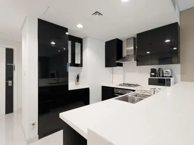 a kitchen with black cabinets and a white counter top at Water Edge Damac Maison Canal View 1BR Perfect Grand Getaway in Dubai