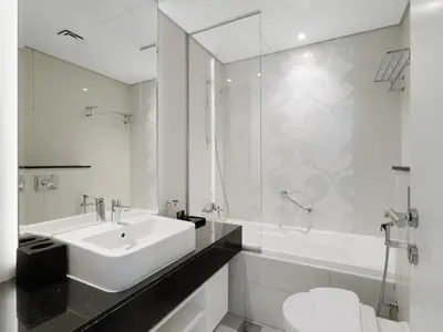 a white bathroom with a sink and a toilet at Water Edge Damac Maison Canal View 1BR Perfect Grand Getaway in Dubai