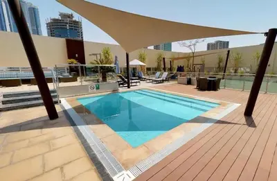 a swimming pool with an umbrella on top of a building at Water Edge Damac Maison Canal View 1BR Perfect Grand Getaway in Dubai