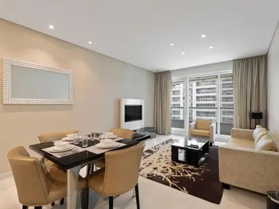 a living room with a table and chairs and a couch at Water Edge Damac Maison Canal View 1BR Perfect Grand Getaway in Dubai