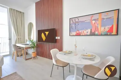 a living room with a white table and chairs at Vogue JVC Luma22 near Circle Mall, Studio Apartment with Balcony and Vibrant Community View, Access to all Amenities in Dubai