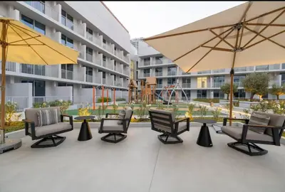 a group of chairs and tables with umbrellas on a patio at Vogue JVC Luma22 near Circle Mall, Studio Apartment with Balcony and Vibrant Community View, Access to all Amenities in Dubai